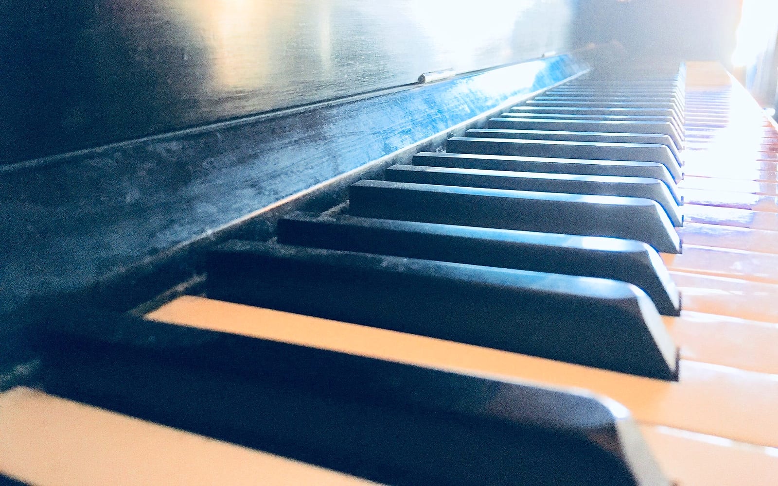 Close-up of worn upright piano keys in warm backlight